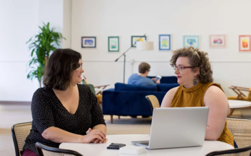 Two people talking in front of a laptop